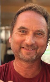 Porträt von Klaus Gaiser mit Anhänger im Hintergrund